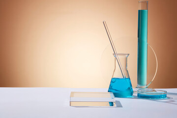 An erlenmeyer flask with a glass rod inside, test tube and petri dish filled with blue fluid....