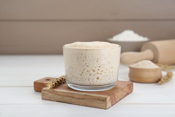 Leaven and ear of wheat on white wooden table
