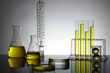 Yellow fluid is contained inside laboratory glassware displayed with a transparent pedestal in...