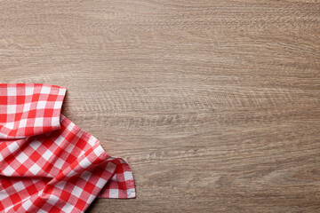 Obraz premium Checkered tablecloth on wooden table, top view. Space for text