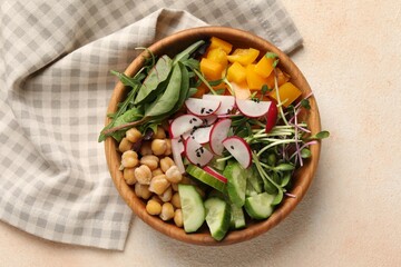 Delicious vegan bowl with cucumbers, chickpeas and radish on beige table, top view