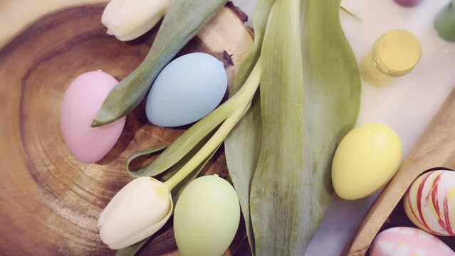 Easter holiday decorations. Easter traditions, painting colorful eggs. Easter Eggs in wooden plate and Spring Flowers on Table. Preparation for Easter.