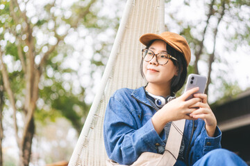 Asian woman relax sitting use smartphone and headphone for mental therapy with at outdoor lifestyle