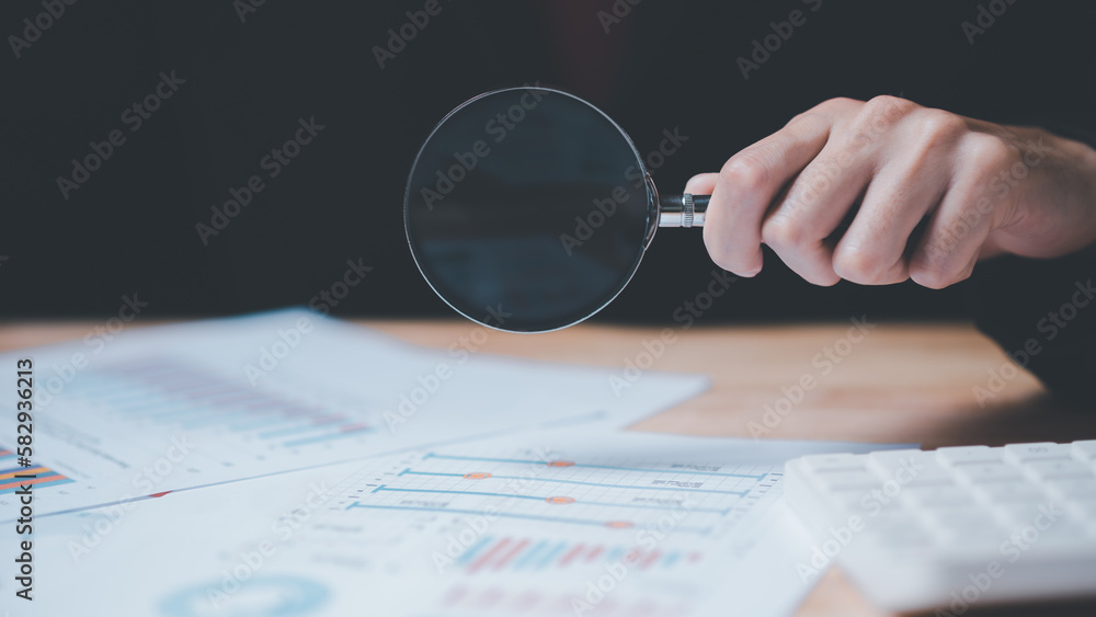 Leinwandbilder businessman holding a magnifying glass showing statistics bar graph inspection and analysis ,analysi