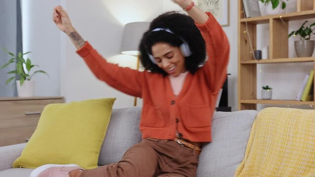 Woman, dancing and music on headphones on a living room sofa with happiness at home. Web radio, online and listening of a happy and relax female in a house on a lounge couch with a dance from audio