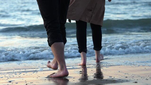 A Couple Walking Barefooted On The Shore With Rough Waves. Slow Motion