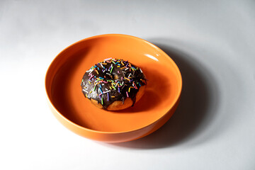 Colourful donut in orange plate on white background. Top view