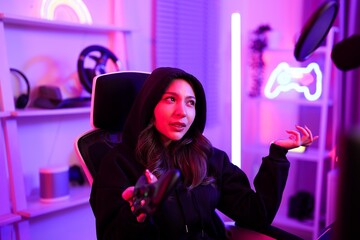 Obraz na płótnie Canvas Asian gamer girl blame and fed up with her team not working support while playing game online in neon violet light room
