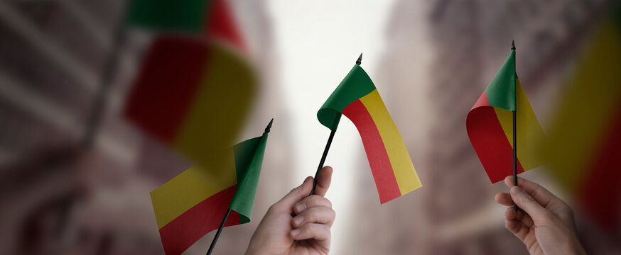 A group of people holding small flags of the Benin in their hands