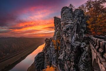Saxon, Germany - Beautiful rock formation of the Bastei bridge with spectacular colorful autumn sunset above Elbe river on a November afternoon in Saxon Switzerland National Park