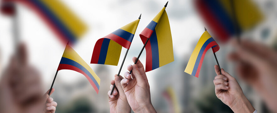 A group of people holding small flags of the Colombia in their hands