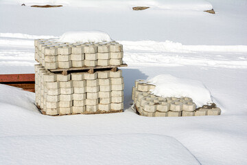 a stack of paving slabs on a construction site covered with snow. 