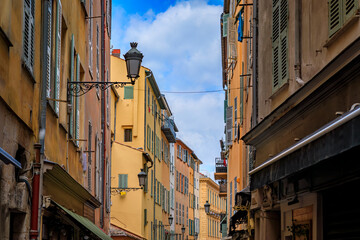Fototapeta na wymiar Traditional old houses on a narrow crooked street in the Old Town, Vieille Ville in Nice, French Riviera, South of France