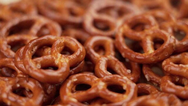 Salted pretzel crackers falling into a heap. Traditional beer snack close up. Rotation. Slow motion