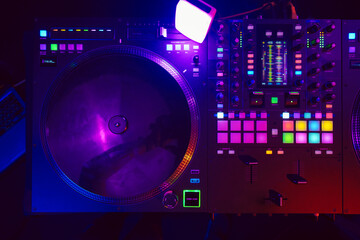 Close up of DJ mixing console in party light