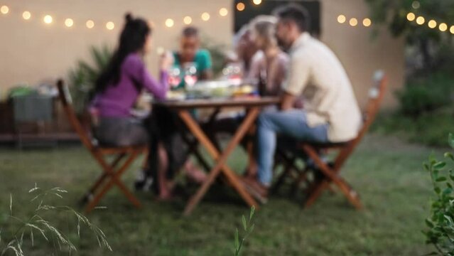 Group of adult Friends eating together at garden dinner during weekend leisure time