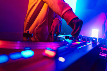Hands of a DJ creating and regulating music on dj console mixer at club concert