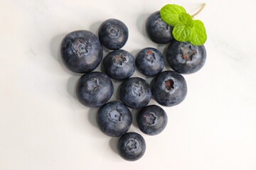 Fresh blueberries with mint leaves. The fruits are actual berries with many tiny seeds and are deep indigo to black color when ripe. Copy space.