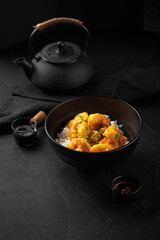 Portion of asian spicy honey shrimp with rice on black background