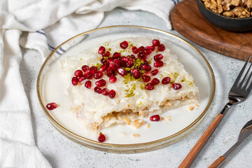 Gullac dessert. Ramadan dessert. Gullac garnished with pomegranate and pistachio in glass plate on gray background. Symbolic food.