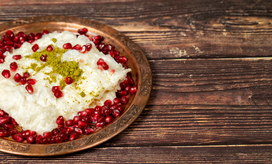 Gullac dessert. Ramadan dessert. Gullac decorated with pomegranate and pistachio on a copper plate on wood background. Symbolic food.