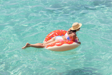 Beautiful woman with inflatable donut in sea