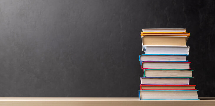 Stack of books on desk with chalkboard - Powered by Adobe