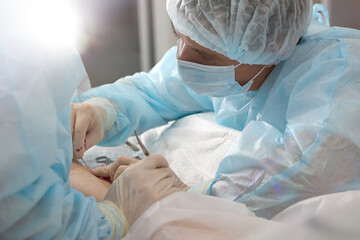 An experienced angiosurgeon operates on the leg of a patient with varicose veins. Doctor in a...