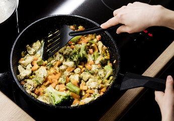 woman cooking vegetables in frying pan