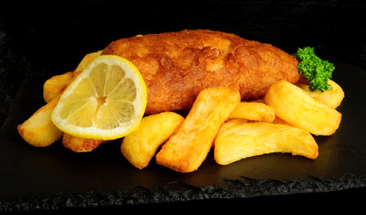 Beer battered cod fish fillet with chunky chips and lemon garnish