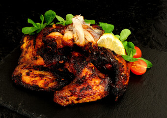 Barbecued chicken wings with lambs lettuce and lemon garnish