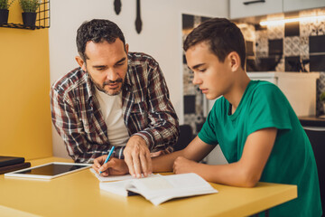 Father is helping his son with learning. They are doing homework together.