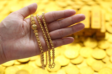 Gold necklaces and stack of coins money on yellow background, Business investment and Saving money for prepare in future concept