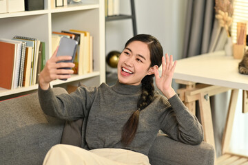 Cheerful woman holding smart phone making video call, talking with friend. People and communication concept