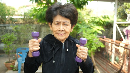 elderly woman holding a dumbbell in order to exercise the arms.