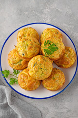 Homemade zucchini muffins with cheese, garlic and herbs on a plate on a gray concrete background. Vegetarian dish. Copy space.