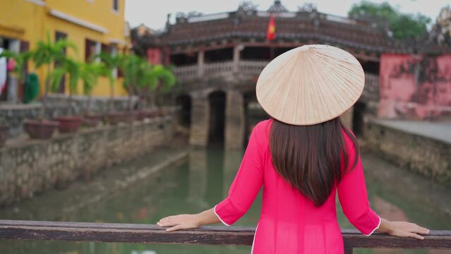 Young female tourist in Vietnamese traditional dress walking at Hoi An Ancient town in Vietnam