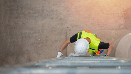 Asian engineer wearing protective vest and white hardhat climbing ladder to go to work. © Digital Art Studio