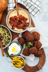 Traditional Shabbat table: challah bread, falafel, quinoa salad, hummus on a wooden board. Israeli food concept.
