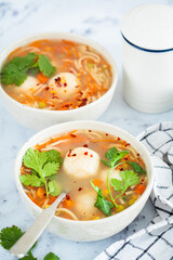 Potato balls soup with noodles and vegetables in white bowl, white background. Vegan food concept.