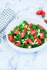 Broccoli salad with cherry tomatoes and almonds in white bowl. Vegan detox recipe.