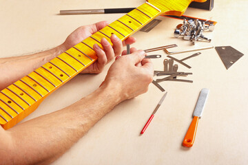 Guitar repairman checks radius of fingerboard of neck electric guitar.