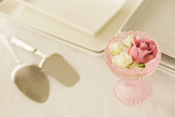 Table setting with rose flower in pink vase and silverware.