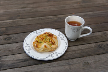 Traditional finnish salty puff pastry with a cup of tea on a wooden table.