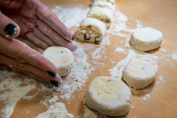 close up of female hand forms a dumpling of cottage cheese dough on a cutting board