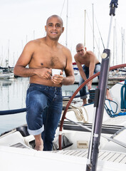 Latin American topless with a cup of coffee in his hand standing on the deck of a yacht in the...