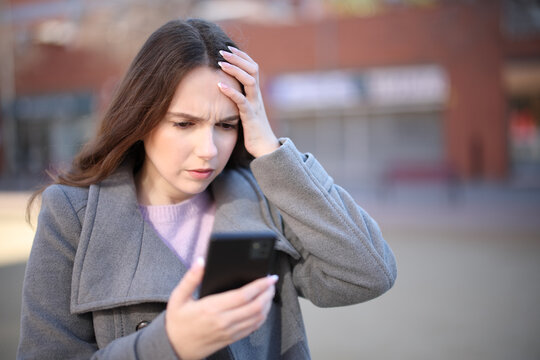 Worried woman checking smart phone in winter