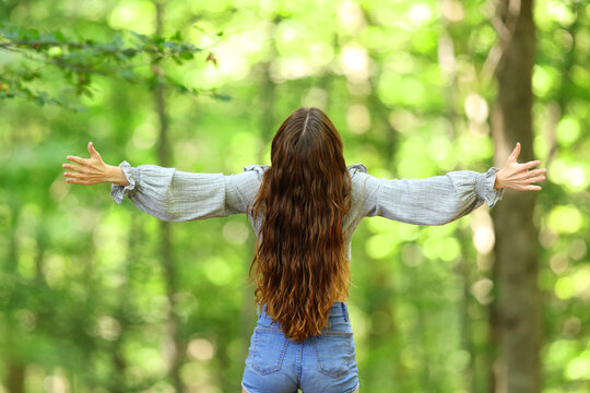 Woman outstretching arms celebrating in a forest