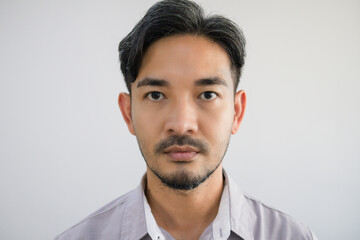 Portrait of a handsome Asian man with a beard in a gray shirt making a straight face.