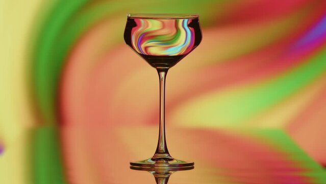 The clear glass is standing infront of a colorful fast moving rainbow background. The reflactions warp with the shape of the glass. High quality 4k footage